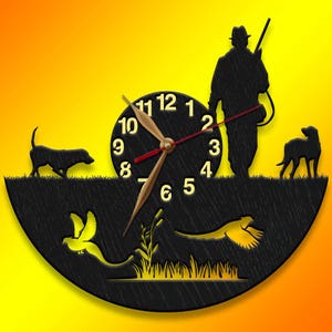 May include: A black wooden clock with a hunter, two dogs, and two birds in silhouette. The clock face has Roman numerals and a red second hand.