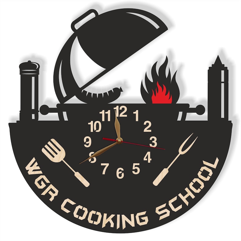 May include: Black and white silhouette of a grill with a clock face in the center. The clock face has Roman numerals and gold hands. The text "WGR COOKING SCHOOL" is written around the clock face.