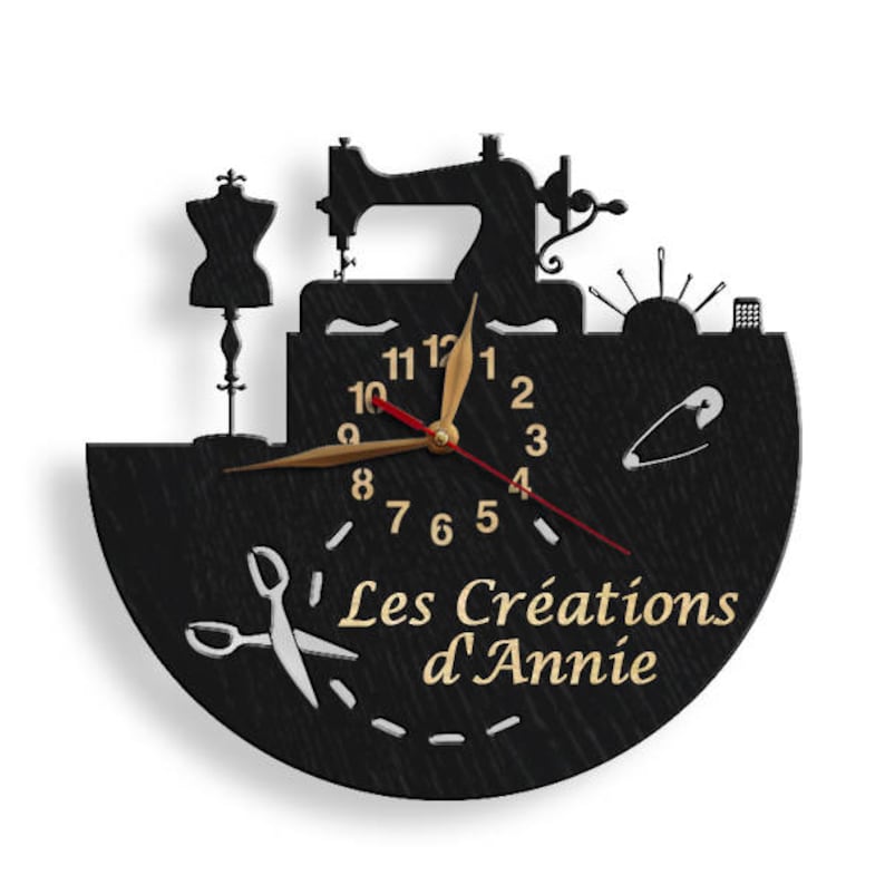 May include: Black wooden clock with a sewing machine, a dress form, and a needle and thread design. The clock face has gold numbers and hands. The clock is inscribed with the text "Les Cr&eacute;ations d'Annie".