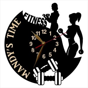 May include: Black and white clock with a dumbbell design. The clock face features the words "Mandy's Time Fitness" and a clock with Roman numerals.