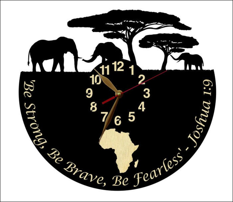 Puede incluir: Reloj negro con un contorno dorado y un mapa de &Aacute;frica dorado en el centro. La esfera del reloj tiene n&uacute;meros blancos y manecillas doradas. El reloj est&aacute; rodeado de un fondo negro con el texto "Be Strong, Be Brave, Be Fearless' - Joshua 1:9" en letras doradas.
