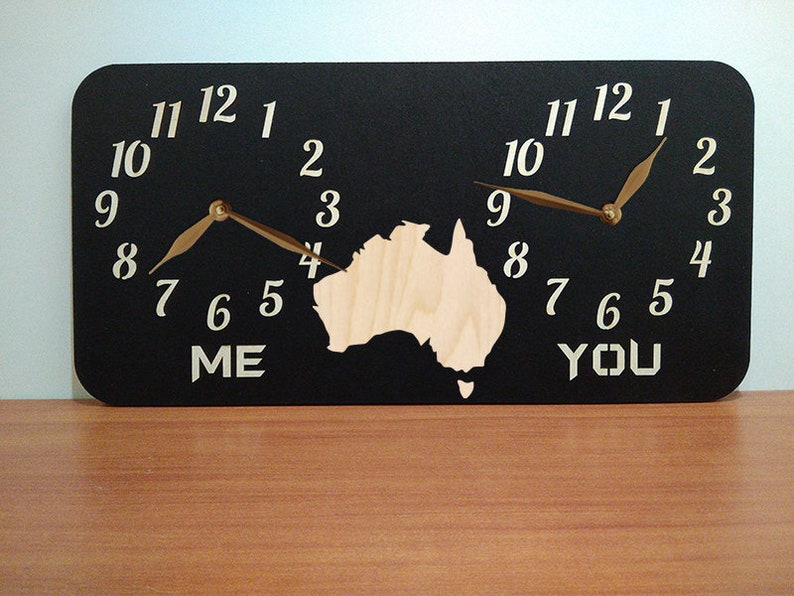 May include: A black wooden clock with two clock faces, one labelled "ME" and the other labelled "YOU". The clock faces are separated by a cutout of the continent of Australia. The clock hands are gold.