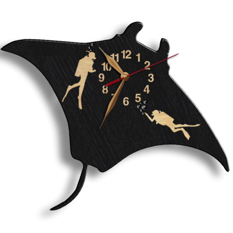 May include: Black wooden wall clock shaped like a manta ray, featuring gold-colored diver silhouettes and clock hands. The clock face has gold numerals and a red second hand. The design evokes a nautical or diving theme.