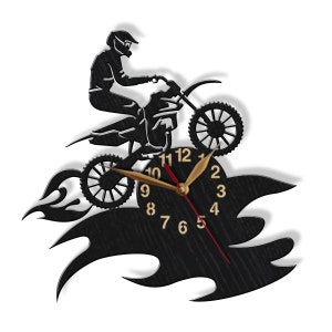 May include: Black and white wall clock featuring a silhouette of a motocross rider jumping over flames. The clock face has black Roman numeral hour markers and gold hands.