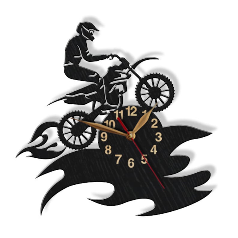 May include: Black and white wall clock featuring a silhouette of a motocross rider jumping over flames. The clock face has black Roman numeral hour markers and gold hands.