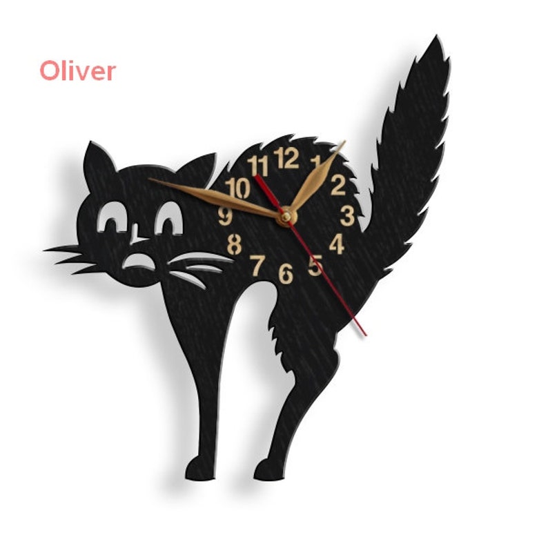 May include: Black silhouette of a cat with a clock face in the center. The clock face has gold numbers and hands. The cat's tail is curled up behind it. The word "Oliver" is written in pink above the cat.