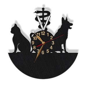 May include: Black wooden clock with a silhouette of a cat and dog, a veterinary symbol, and the numbers 1-12. The clock hands are gold and red.
