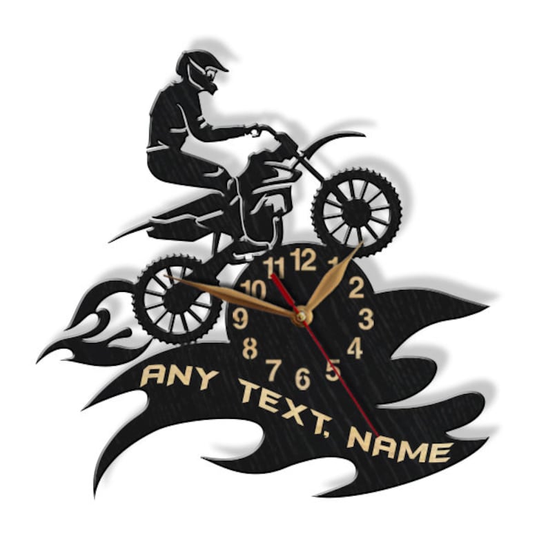 May include: Black and gold wall clock featuring a silhouette of a motocross rider jumping over flames. The clock face has black Roman numeral hour markers and gold hands. The clock face also includes the text "ANY TEXT, NAME".