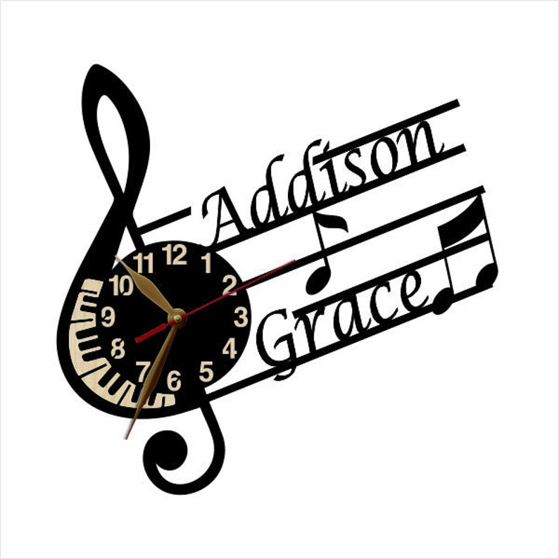Puede incluir: Reloj blanco y negro con un dise&ntilde;o de clave de sol. La esfera del reloj tiene un dise&ntilde;o de teclas de piano y las palabras "Addison Grace" est&aacute;n escritas en la clave de sol.