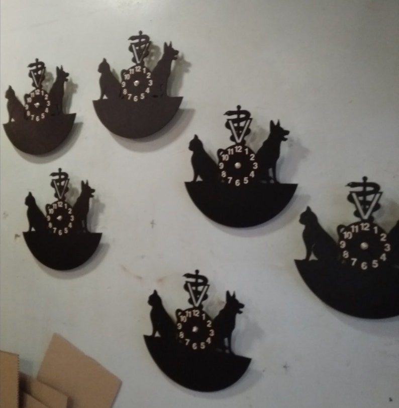 May include: Five black vinyl record clocks with a veterinarian symbol and silhouettes of a cat and dog. The clocks have white numbers and hands.