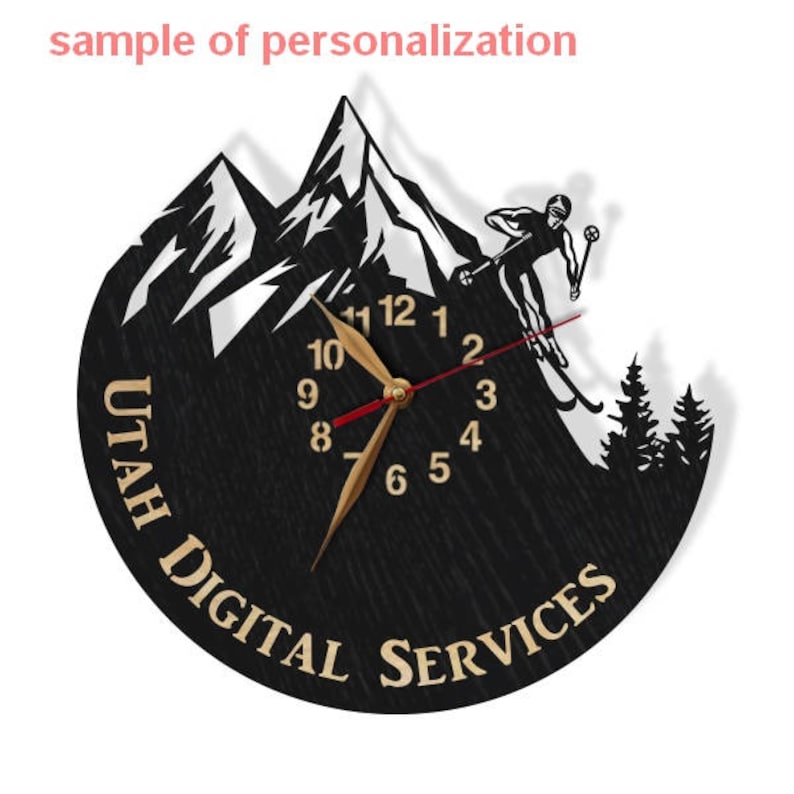 Puede incluir: Un reloj de madera negro con una escena de monta&ntilde;a blanca y un esquiador. La esfera del reloj tiene n&uacute;meros y manecillas dorados. El texto "UTAH DIGITAL SERVICES" est&aacute; escrito en dorado alrededor de la esfera del reloj.