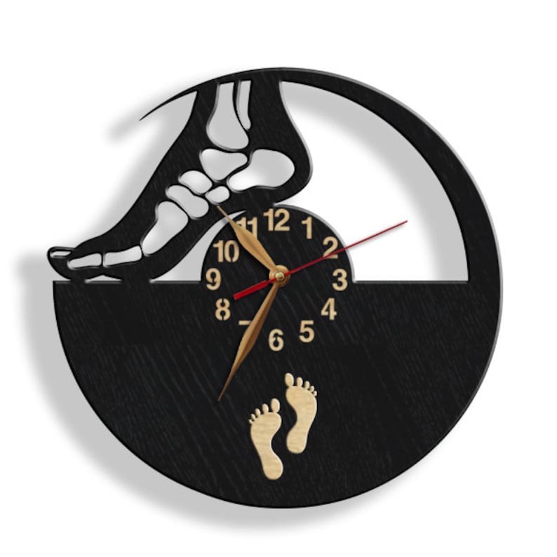 May include: A black and white wall clock with a unique design featuring a foot skeleton and a clock face. The clock hands are gold, and the second hand is red. Two gold footprints are at the bottom.
