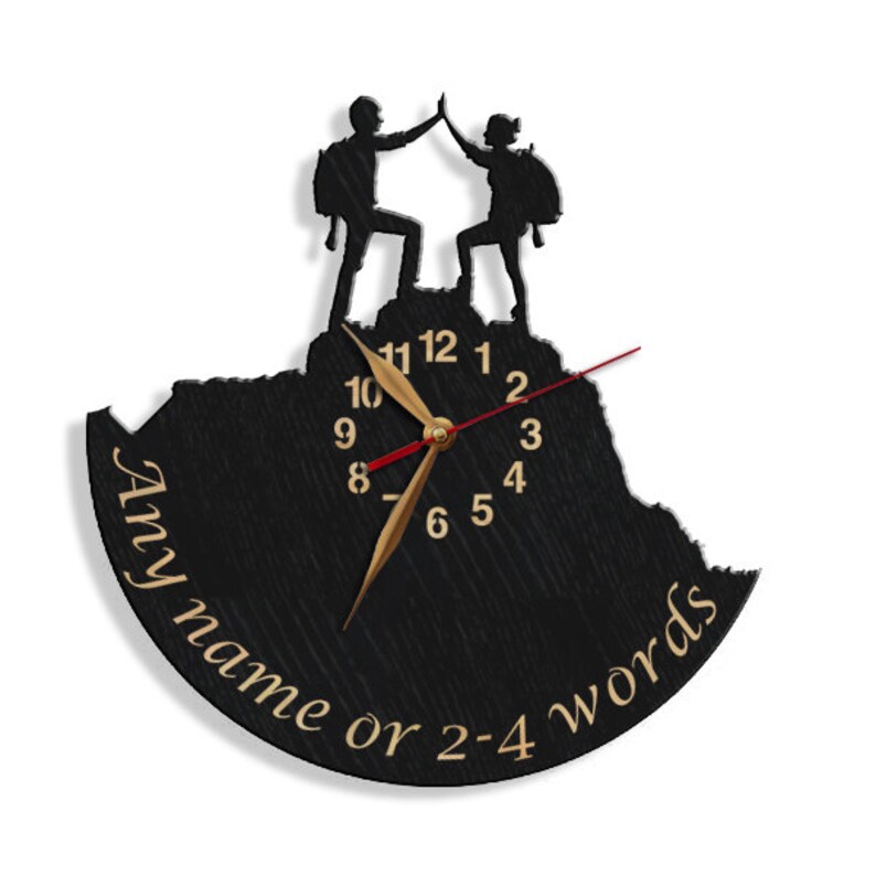 May include: Black wooden clock with a silhouette of two people high-fiving on a mountain top. The clock face has gold hands and black numbers. The clock has a personalized inscription that reads "Any name or 2-4 words".