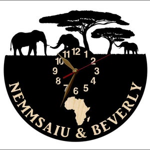 Puede incluir: Reloj de silueta en blanco y negro con un dise&ntilde;o de continente africano de madera. La esfera del reloj tiene n&uacute;meros romanos negros y una manecilla de reloj roja y dorada. El reloj est&aacute; rodeado de una silueta negra de tres elefantes y tres &aacute;rboles. El texto "Nemmsaiu & Beverly" est&aacute; escrito alrededor de la esfera del reloj.