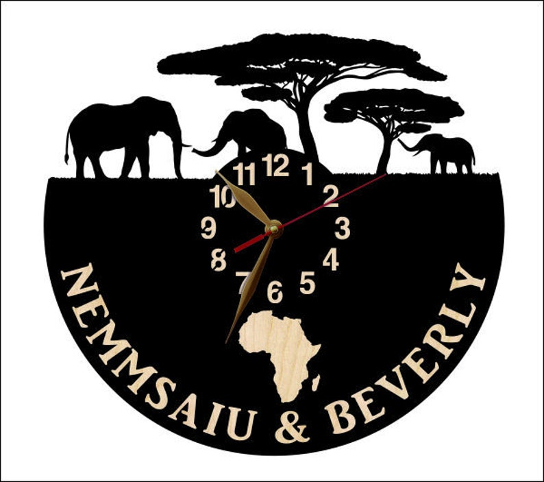 Puede incluir: Reloj de silueta en blanco y negro con un dise&ntilde;o de continente africano de madera. La esfera del reloj tiene n&uacute;meros romanos negros y una manecilla de reloj roja y dorada. El reloj est&aacute; rodeado de una silueta negra de tres elefantes y tres &aacute;rboles. El texto "Nemmsaiu & Beverly" est&aacute; escrito alrededor de la esfera del reloj.