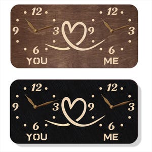 May include: Two wooden wall clocks, one brown and one black, each with a heart design and the words "YOU" and "ME". The clocks have gold-coloured hands and hour markers.