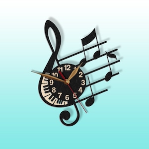 Puede incluir: Reloj de pared de madera negro con forma de clave de sol con notas musicales y un dise&ntilde;o de teclado de piano. La esfera del reloj tiene n&uacute;meros blancos y manecillas doradas.