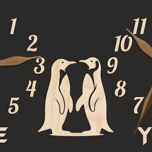 May include: A black wooden clock with two penguin silhouettes in the centre. The clock faces read "ME" and "YOU" with the numbers 1 through 12 around each clock face.