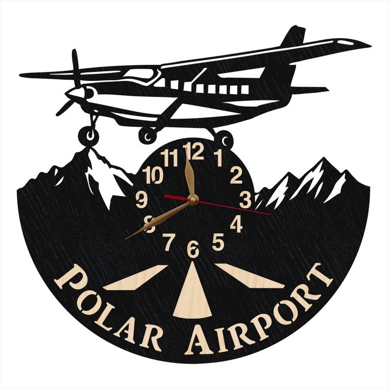 May include: Black and white clock with a silhouette of a small plane flying over mountains. The clock face has a wooden runway design and the words "POLAR AIRPORT" printed on the bottom.