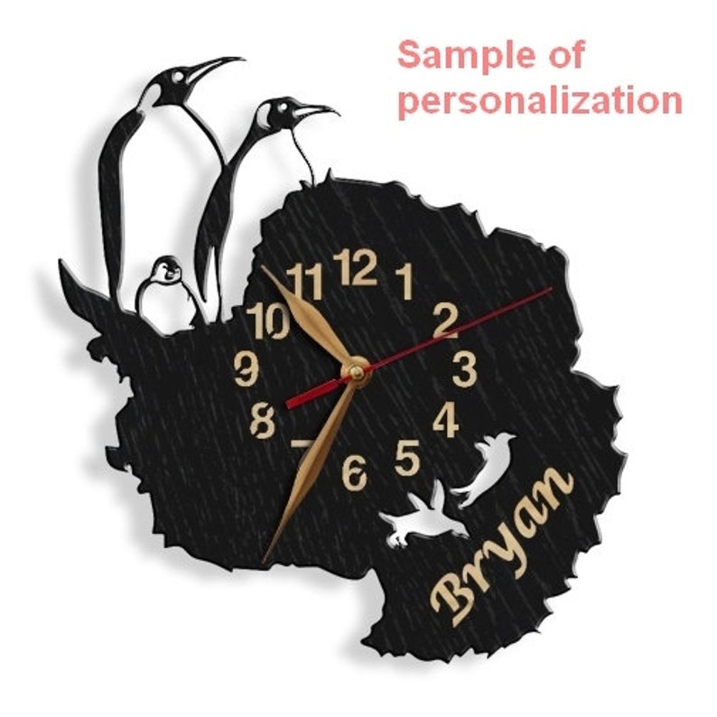 May include: Black wooden clock shaped like the continent of Antarctica with a gold clock face and hands. The clock has a white penguin silhouette and the name "Bryan" written in gold lettering.