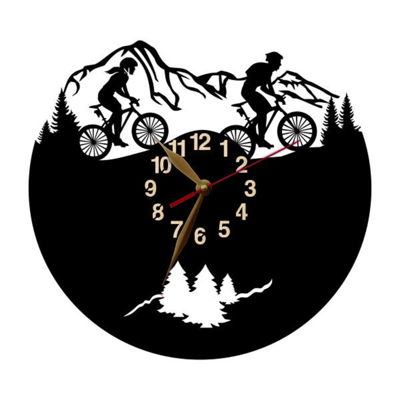 May include: Black wall clock featuring a mountain biking theme. The clock face is black with gold-colored hands and numbers. Silhouettes of cyclists and mountain scenery are incorporated into the design, creating a unique decorative piece.