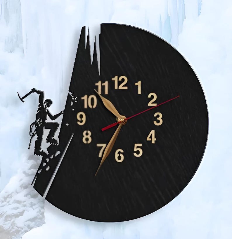 May include: Black clock with gold numbers and hands, featuring a silhouette of a climber scaling a rock face. The clock is shaped like a mountain with an icicle hanging from the top.