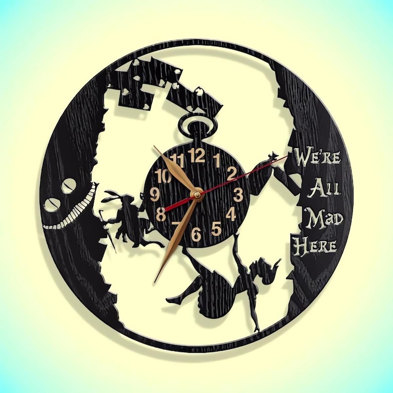 May include: Black wooden clock with a silhouette of Alice falling down a rabbit hole. The clock face features Roman numerals and the text "We're All Mad Here".