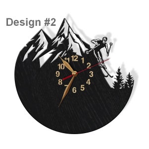 Puede incluir: Reloj negro con una escena de monta&ntilde;a blanca y un esquiador en silueta. La esfera del reloj tiene n&uacute;meros y manecillas dorados. El reloj tiene un di&aacute;metro de 30 cm.