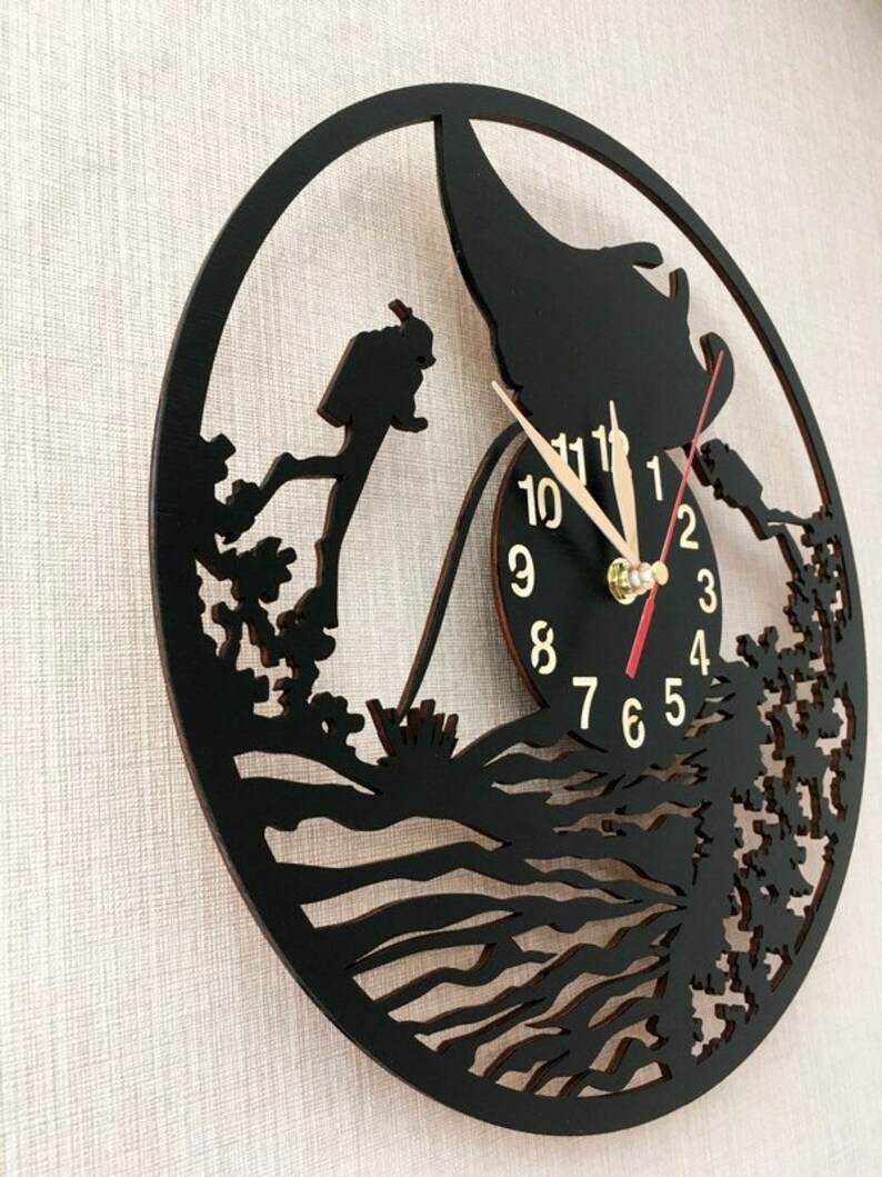 May include: Black wooden wall clock with a silhouette of a person diving into the ocean. The clock face has gold numbers and hands.
