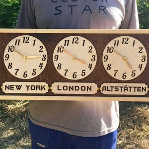 May include: A rectangular wooden wall clock featuring five circular clock faces with light wood backgrounds and black numerals. Each clock has gold-colored hands and a rectangular label below reading SEATTLE, NEW YORK, LONDON, ALTSTÄTTEN, and TOKYO.