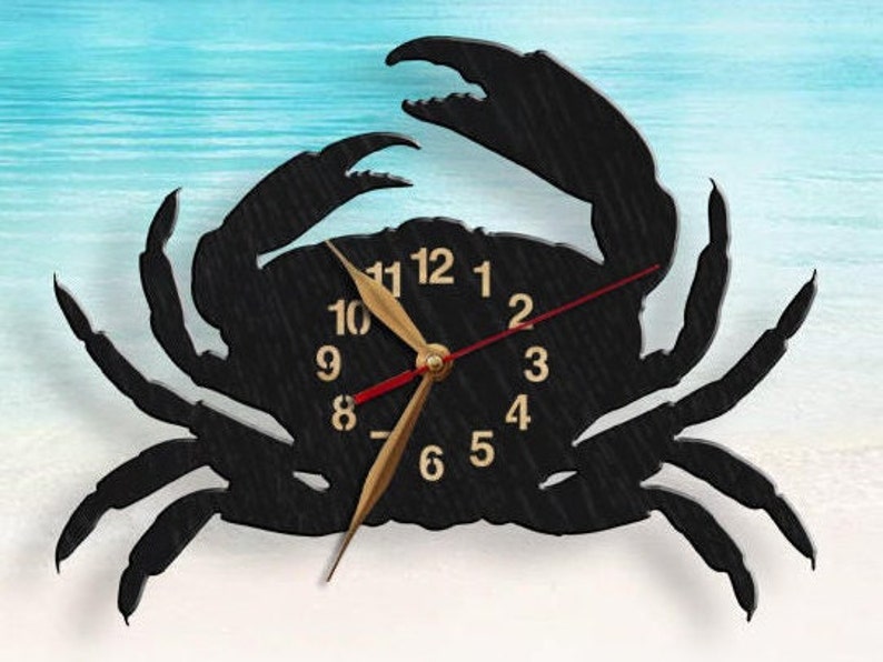 May include: A black wall clock shaped like a crab with a textured surface. The clock face features gold-colored numbers from 1 to 12, two gold-colored hour and minute hands, and a thin red second hand centered on the crab's body.