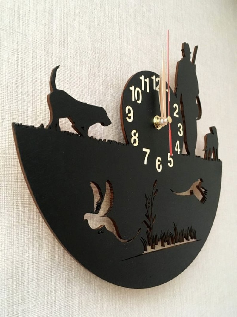 May include: Black wooden clock with a hunter, two dogs, and birds in flight. The clock face has gold numbers and hands.