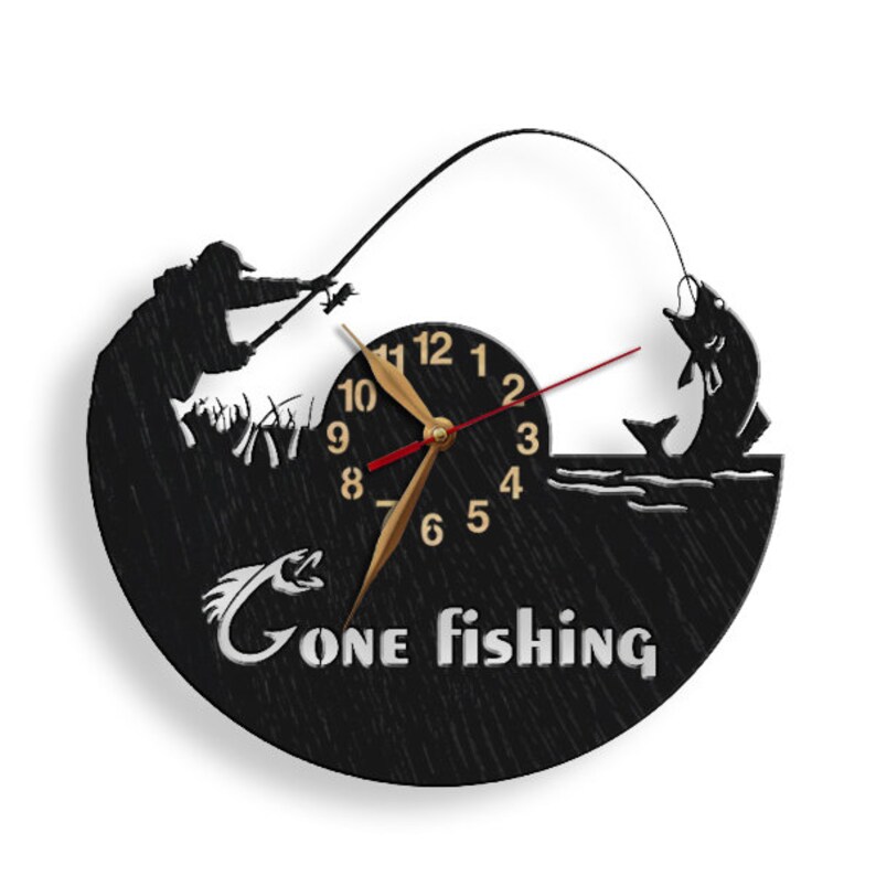May include: Black and white wall clock with a silhouette of a fisherman casting a line and a fish jumping out of the water. The clock face has gold numbers and hands. The text "Gone Fishing" is printed below the clock face.