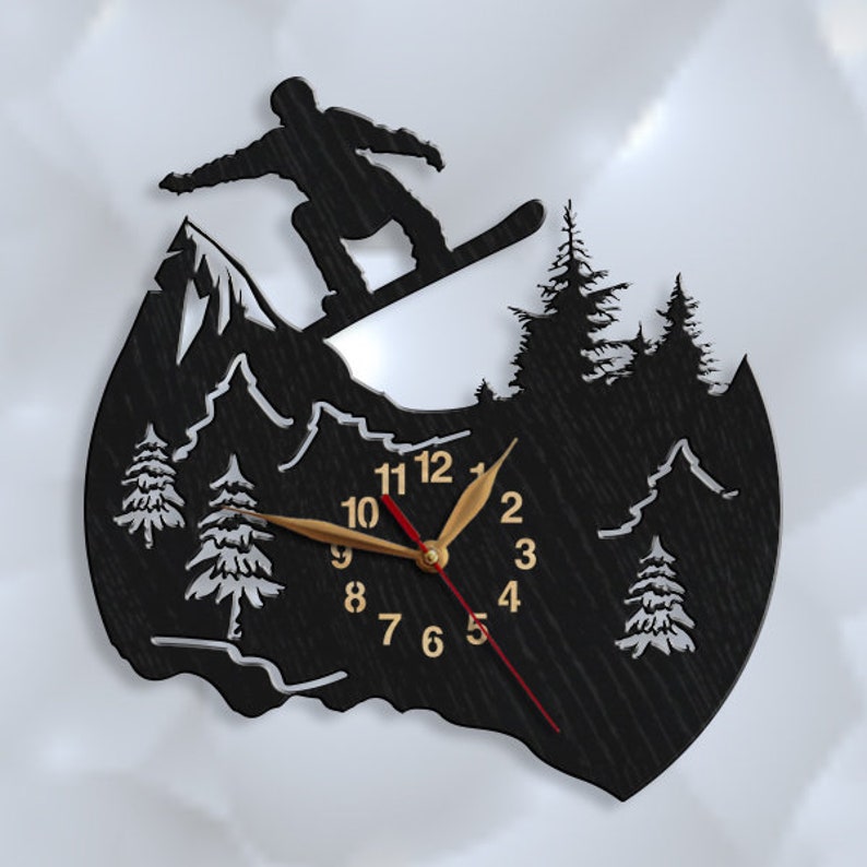 May include: Black wooden clock with a silhouette of a snowboarder on a mountain. The clock face has gold numbers and hands, and a red second hand.