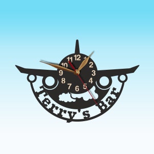 May include: Black airplane-shaped wall clock with gold hands and a white cloud design. The clock face has the text "Terry's Bar" around the edge.
