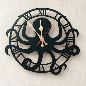 May include: A black, laser-cut wall clock with an octopus design. The clock has Roman numerals around the edge and gold-coloured clock hands. The octopus's tentacles form the clock's face, creating a unique and artistic timepiece.