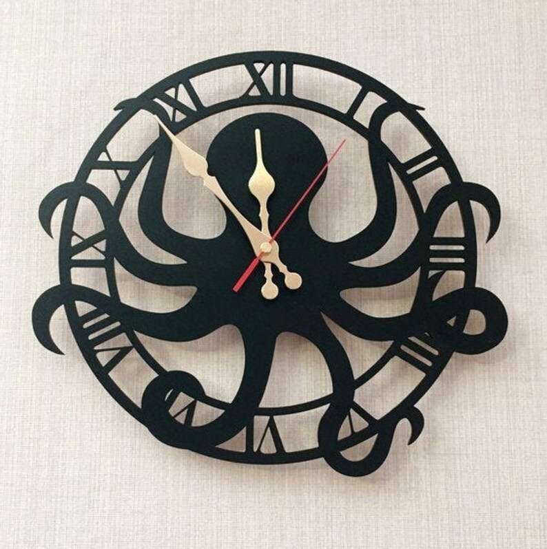 May include: A black, laser-cut wall clock with an octopus design. The clock has Roman numerals around the edge and gold-coloured clock hands. The octopus's tentacles form the clock's face, creating a unique and artistic timepiece.