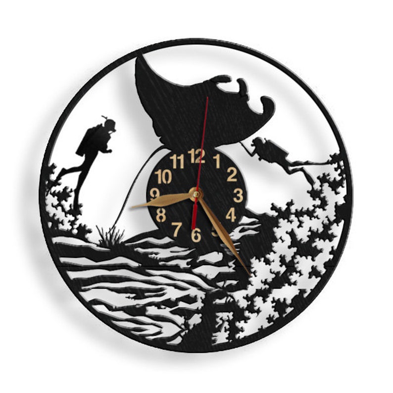 May include: Black and white wall clock with a silhouette of a manta ray and two scuba divers. The clock face has gold numbers and hands.