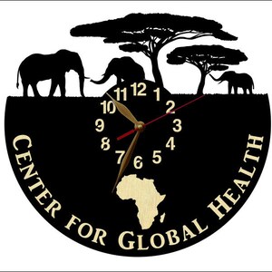 Puede incluir: Reloj negro con una silueta de elefantes y &aacute;rboles. La esfera del reloj tiene n&uacute;meros y manecillas dorados. El reloj est&aacute; rodeado por el texto "Center for Global Health".