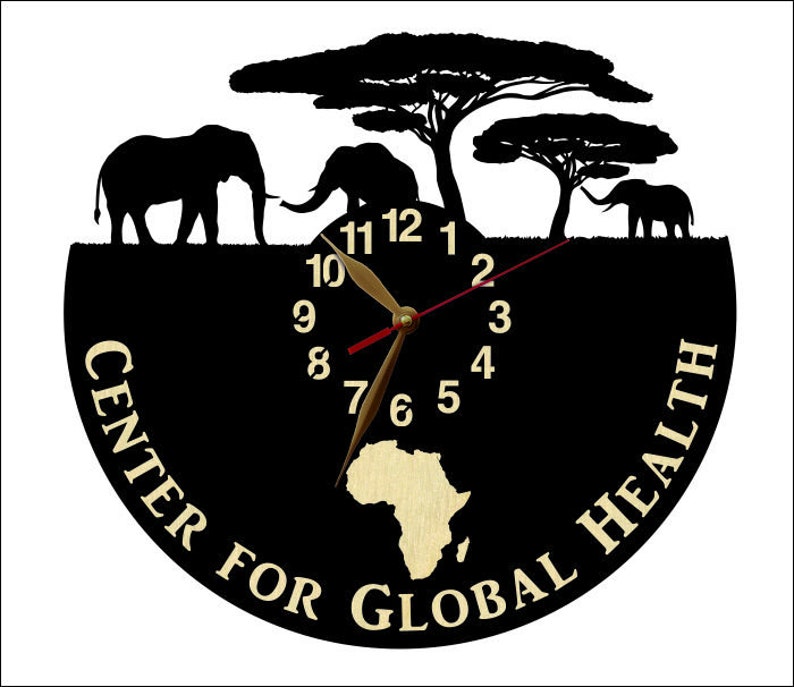 Puede incluir: Reloj negro con una silueta de elefantes y &aacute;rboles. La esfera del reloj tiene n&uacute;meros y manecillas dorados. El reloj est&aacute; rodeado por el texto "Center for Global Health".