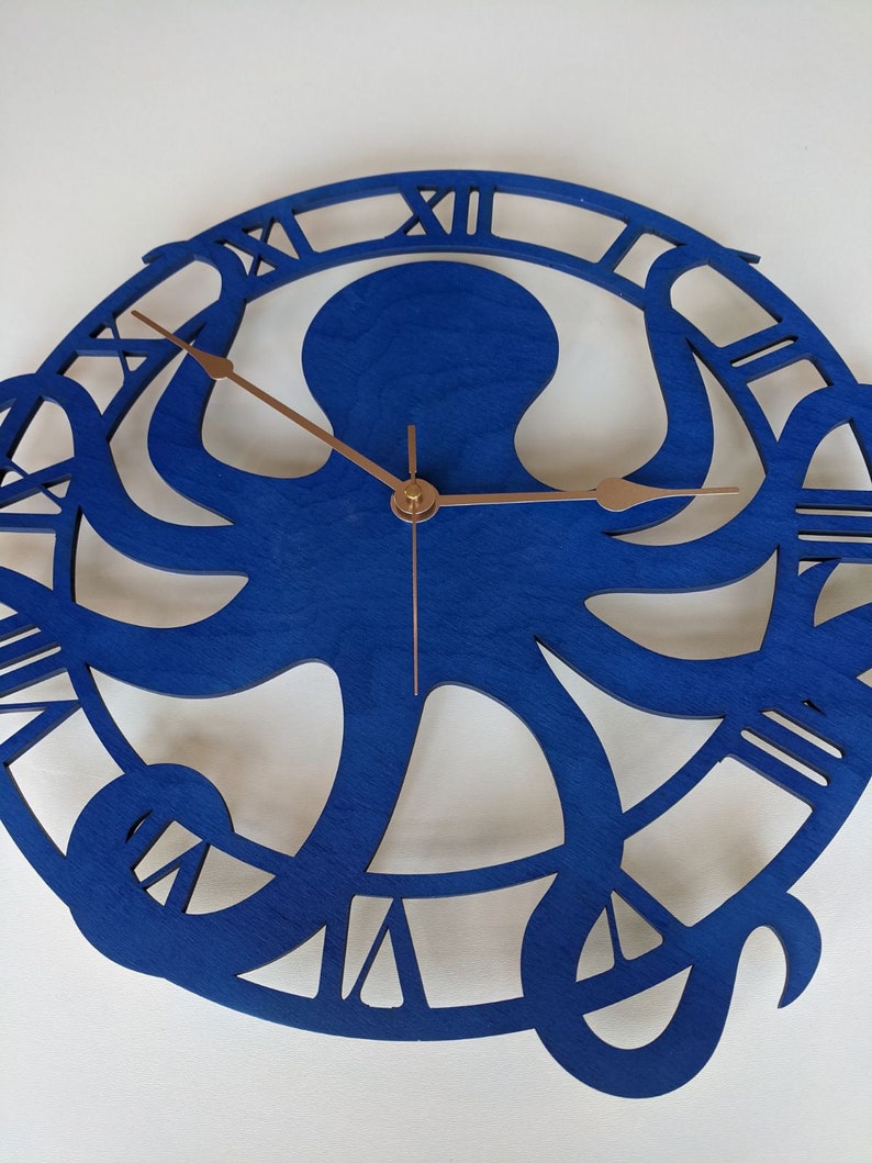 May include: A blue wooden wall clock with an octopus design. The clock face features Roman numerals and bronze hands. The octopus is the central design, with its tentacles forming the clock's frame.
