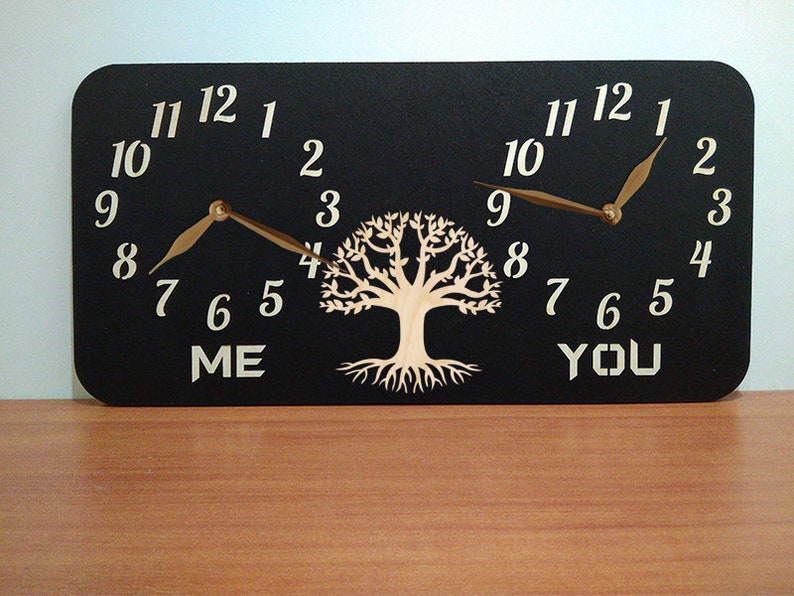 May include: A black wooden clock with two clock faces, one labelled "ME" and the other "YOU". The clock faces are surrounded by a tree design with roots.