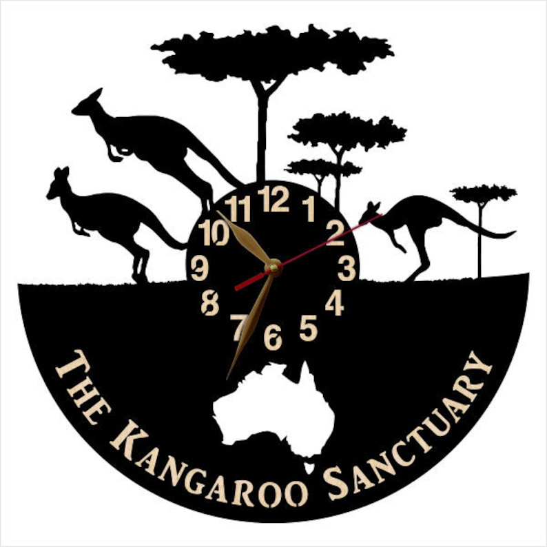 May include: Black and white clock with a silhouette of kangaroos and trees. The clock face has a black background with white numbers and gold hands. The clock is surrounded by a black circle with the text "The Kangaroo Sanctuary" in white.