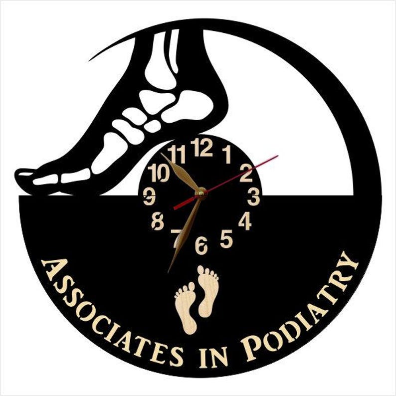 May include: A black and tan wall clock with a podiatry theme. The clock features a silhouette of a foot skeleton, a clock face, and the words "Associates in Podiatry". The clock hands are gold.