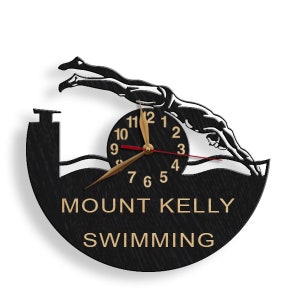 May include: Black and gold clock with a silhouette of a swimmer diving into a pool. The clock face reads "MOUNT KELLY SWIMMING".