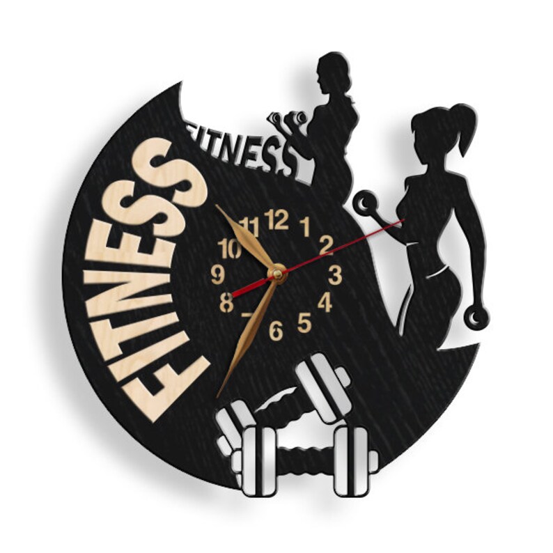 K&ouml;nnte beinhalten: Schwarze und wei&szlig;e Wanduhr mit Holzmaserung. Das Zifferblatt der Uhr zeigt eine Uhr mit r&ouml;mischen Ziffern und eine Silhouette von zwei Frauen, die Gewichte heben. Die Uhr ist von dem Wort "FITNESS" in Holzmaserung umgeben.