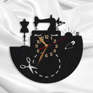 May include: Black wooden wall clock with a sewing machine, a dress form, scissors, and a pin design. The clock face has gold numbers and hands.