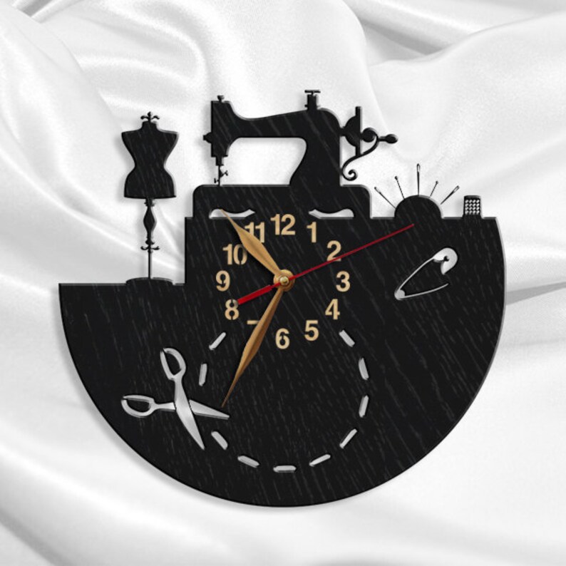 May include: Black wooden wall clock with a sewing machine, a dress form, scissors, and a pin design. The clock face has gold numbers and hands.