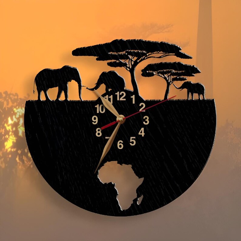 Puede incluir: Reloj de madera negro con un contorno del continente africano y tres elefantes en silueta sobre un fondo de puesta de sol. La esfera del reloj tiene n&uacute;meros romanos y manecillas doradas.