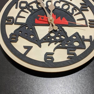May include: A wooden clock with a pizza design. The clock face features a pizza with cheese and pepperoni, a red flame, and the word "Pizza" written around the edge. The clock hands are black and gold.